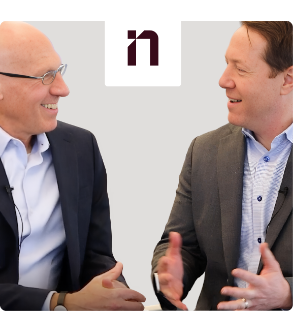 Two men in business attire engaging in a friendly conversation, with the linkedin logo visible between them, against a neutral background.
